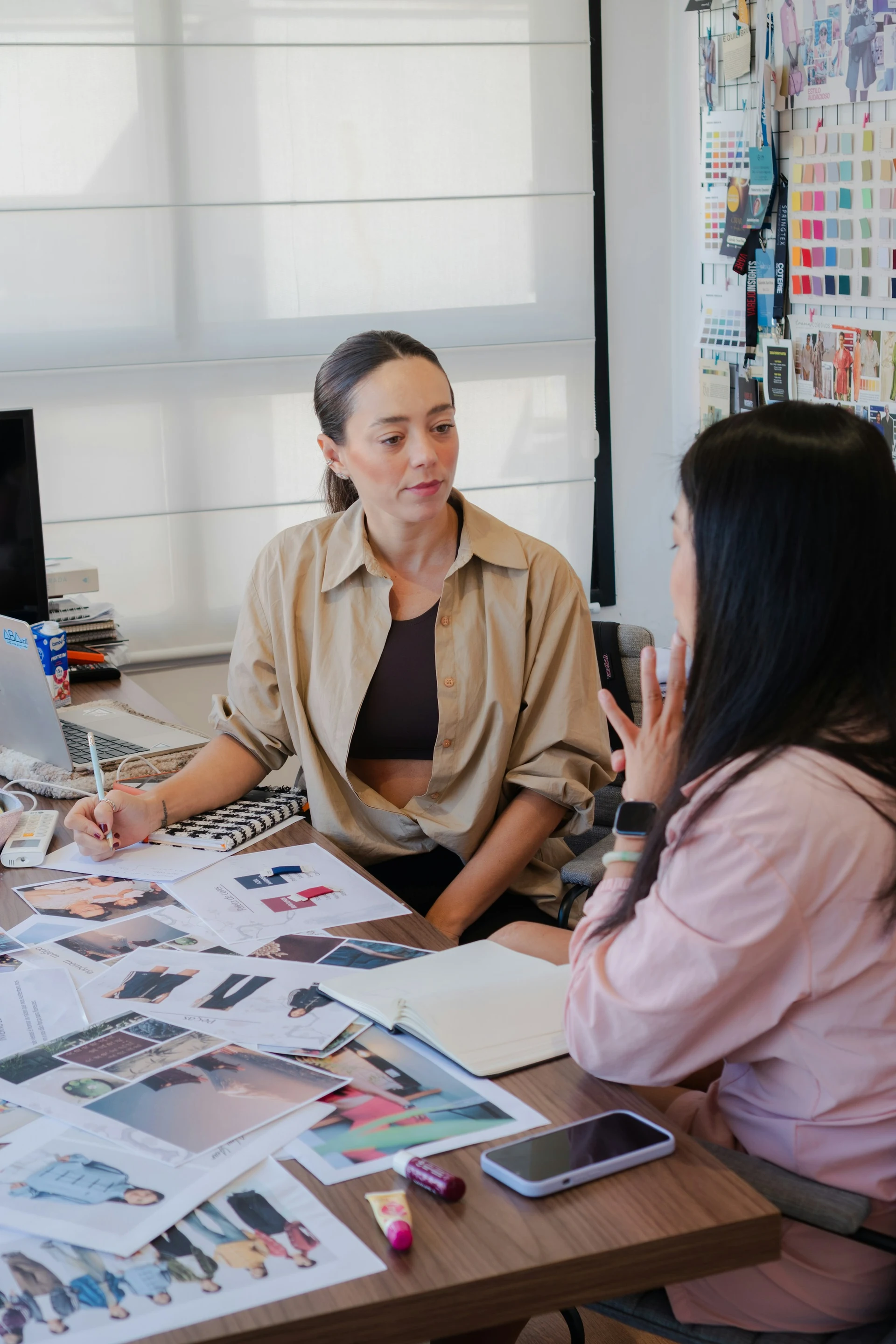 Two designers discussing visual references and materials at a studio table