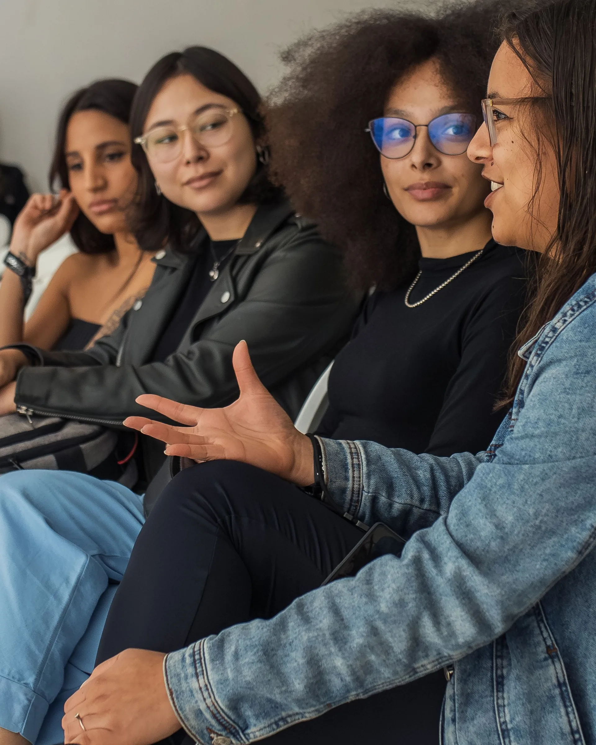 People of different backgrounds seated together in conversation, one woman speaking to the group