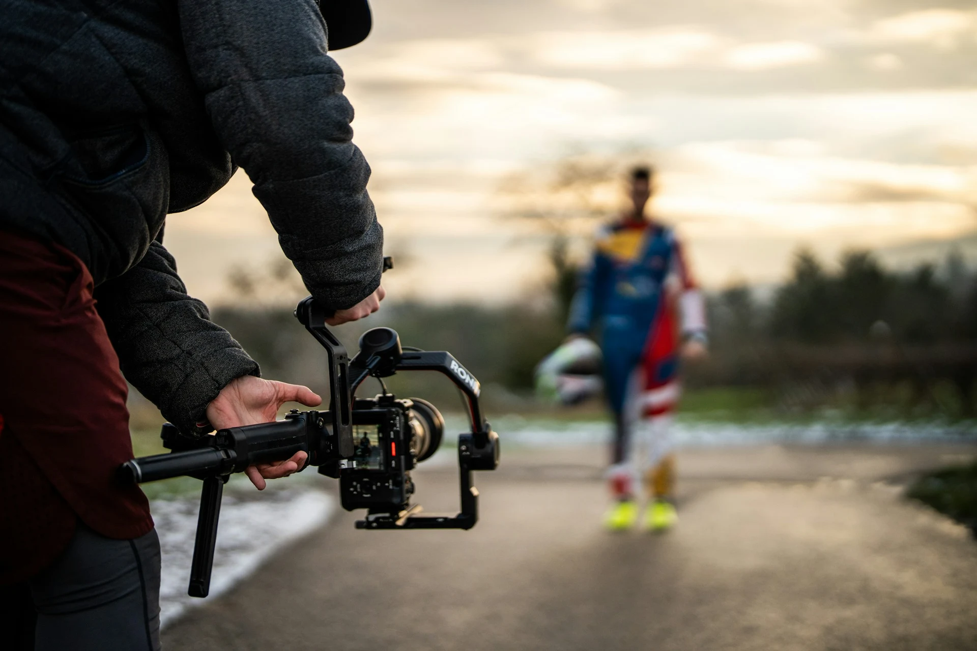A camera operator filming outdoors with a handheld stabiliser